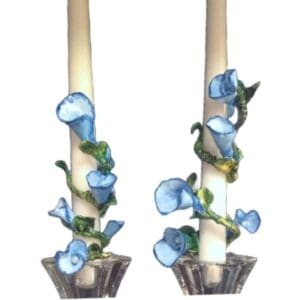 A pair of candles with blue flowers in them.