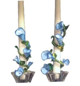 A pair of candles with blue flowers in them.