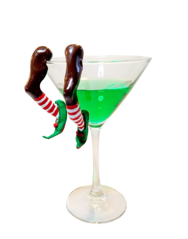 A glass of green liquid with chocolate legs on top.