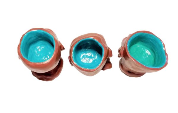 Three cups with a blue interior are sitting on the floor.