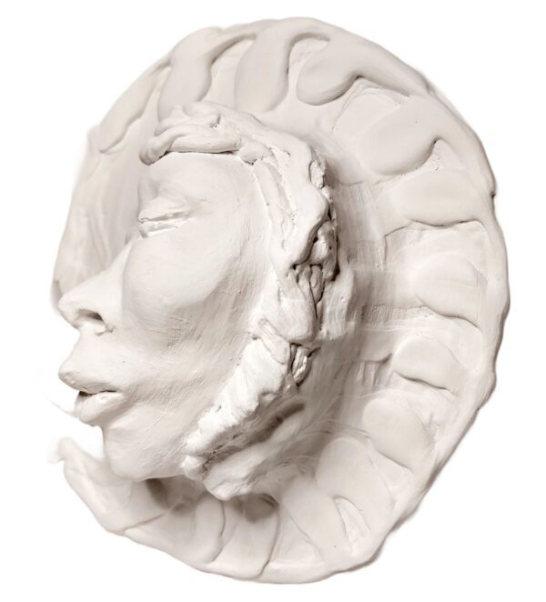 A white sculpture of a face with a hat on it.