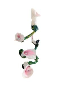 A long white and pink flower sculpture hanging from the side of a wall.