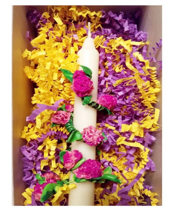 A candle with flowers on it in the middle of some yellow and purple paper.