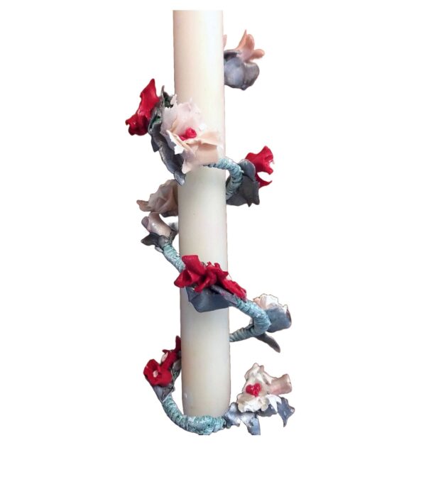 A candle with red and blue flowers on it.