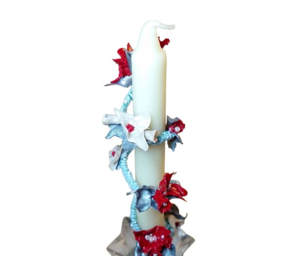 A candle with red and blue flowers on it.