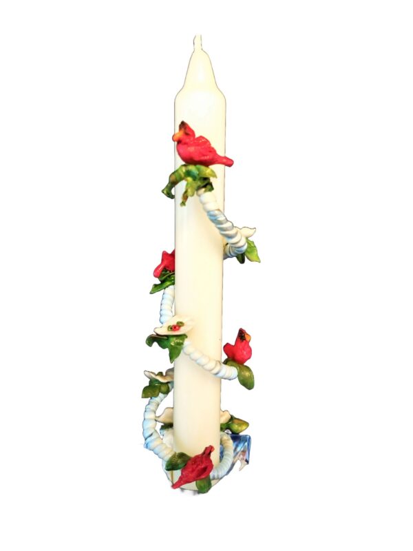 A candle with red flowers and green leaves.