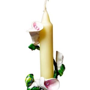 A candle with flowers and leaves around it.