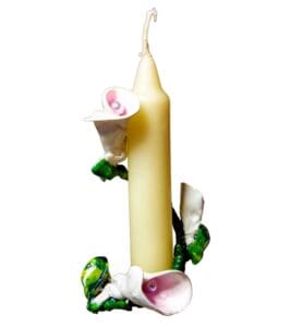 A candle with flowers and leaves around it.