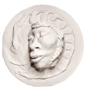 A white round sculpture of a face with a crown on it.