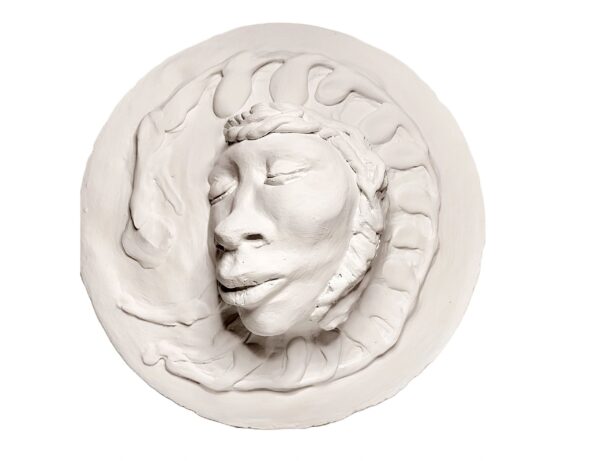 A white round sculpture of a face with a crown on it.