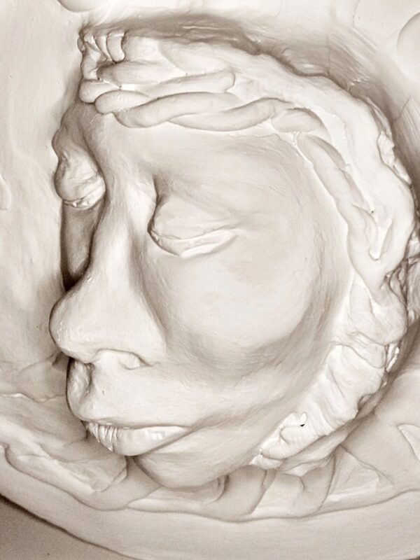 A white sculpture of a face with long hair.