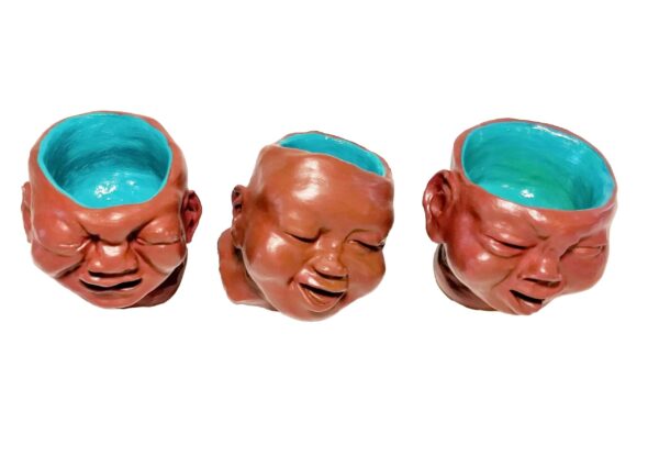 Three ceramic heads with blue paint on them.