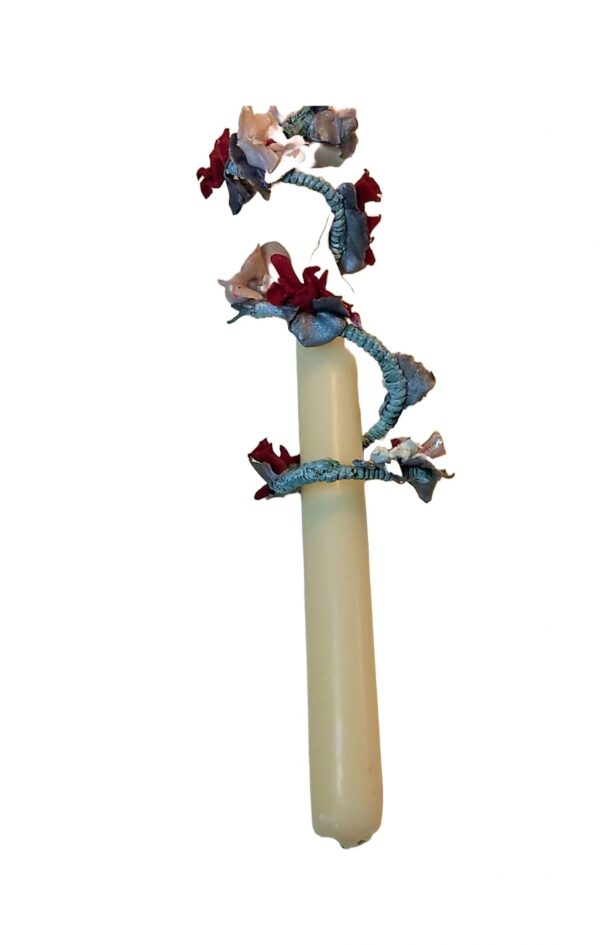 A tall candle with red and blue flowers on it.