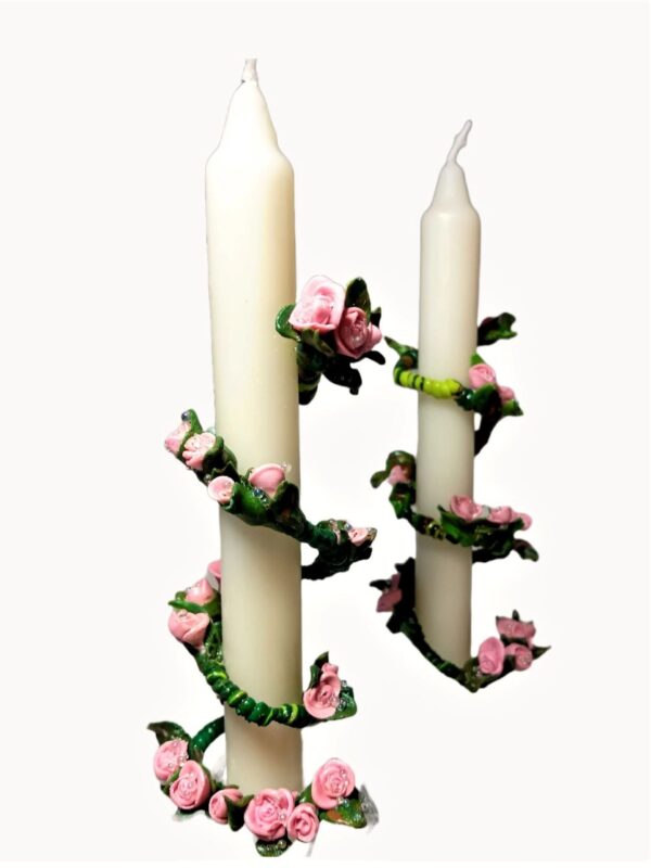 A pair of candles with pink flowers on them.
