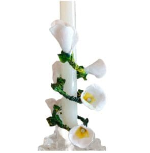 A candle with white flowers and green leaves.