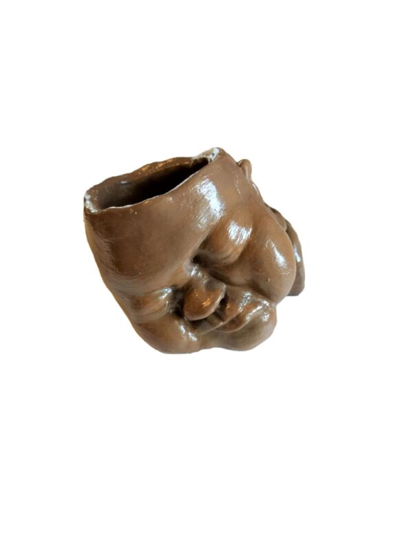 A brown ceramic hand sculpture sitting on top of a table.