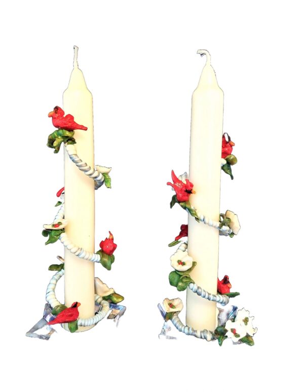 A pair of candles with flowers and ribbons.