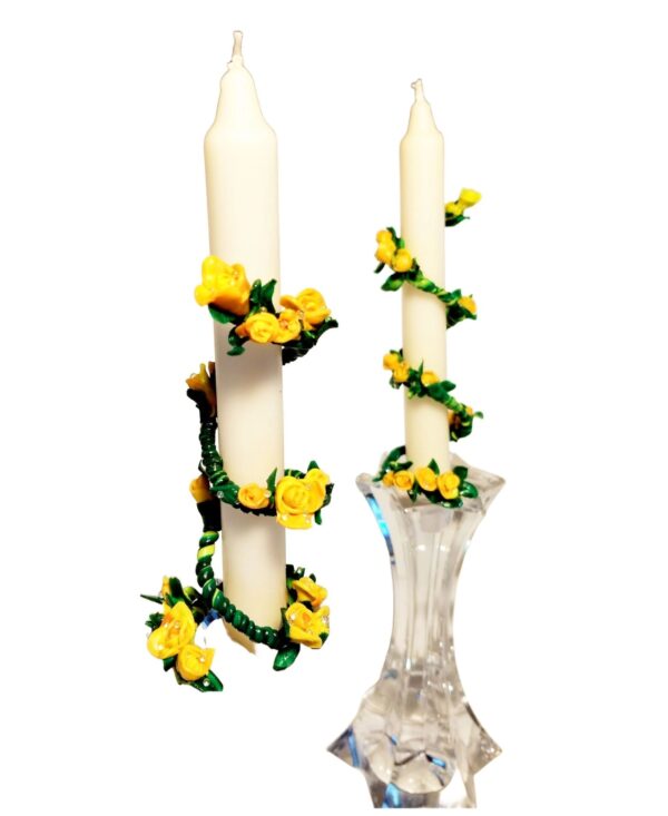 A pair of candles with yellow flowers in the middle.