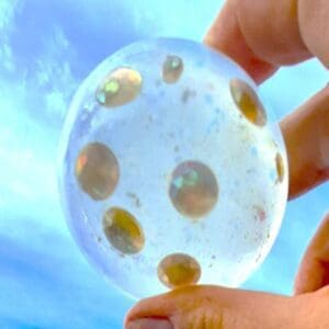 A person holding a bubble with gold dots on it.