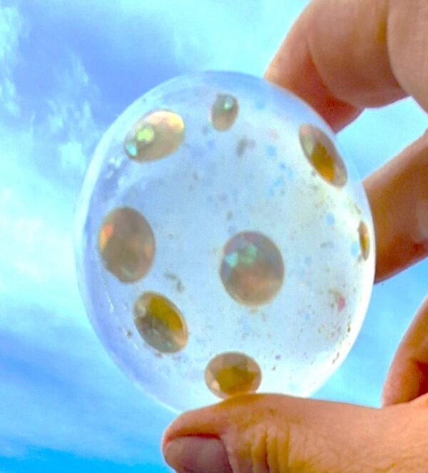 A person holding a bubble with gold dots on it.
