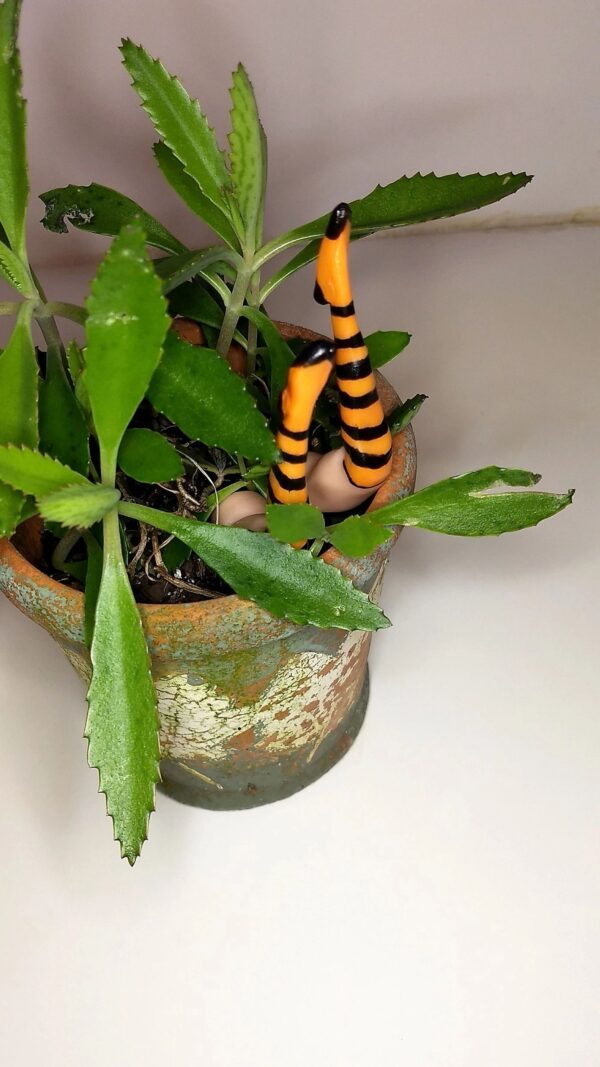 A plant in a pot with fake bugs on it.