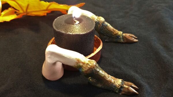 A candle is lit in front of an animal leg.
