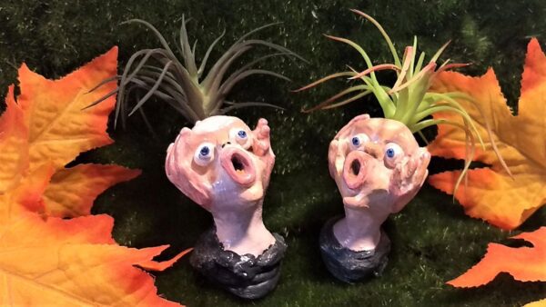 Two ceramic heads with plants growing in them.