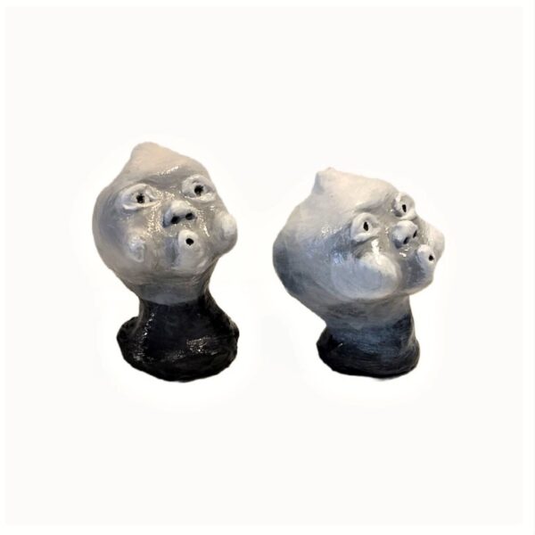 Two ceramic heads are sitting on a black base.