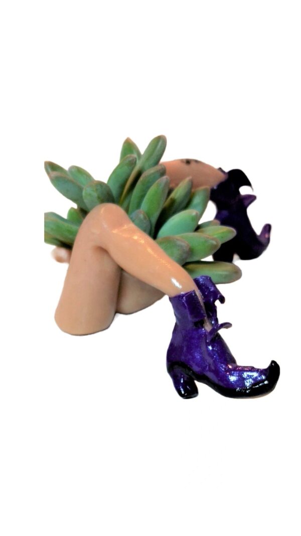 A woman with purple boots and a bunch of green bananas.