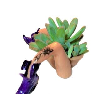 A hand holding a plant with a tattoo on it.