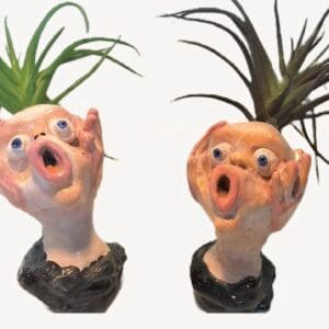 Two ceramic heads with plants growing on them.