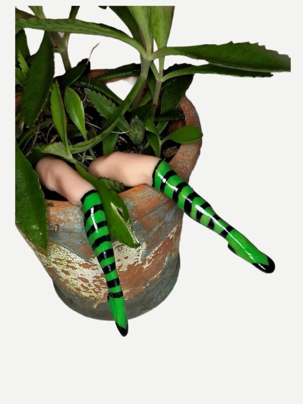 A hand holding two green and black striped sticks in a pot.