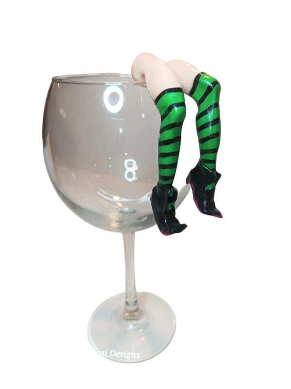 A glass of wine with a woman 's legs hanging over the top.