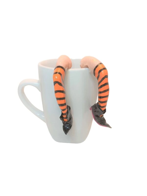 A cup with two orange and black striped snake bracelets on it.
